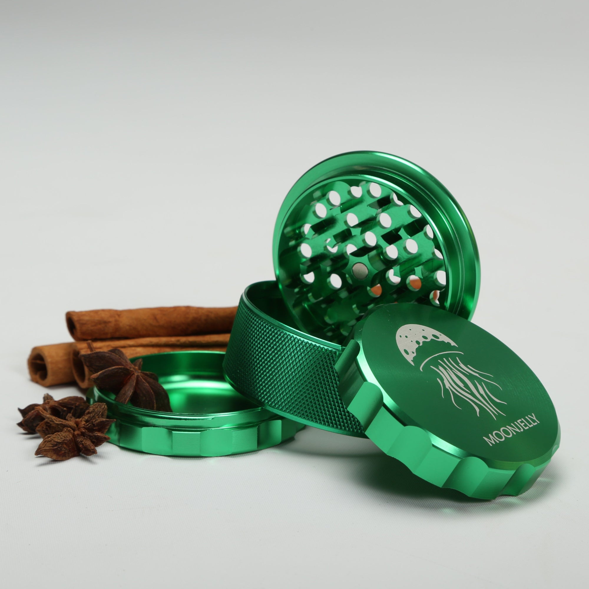 Green herb grinder with cinnamon sticks and star anise on a