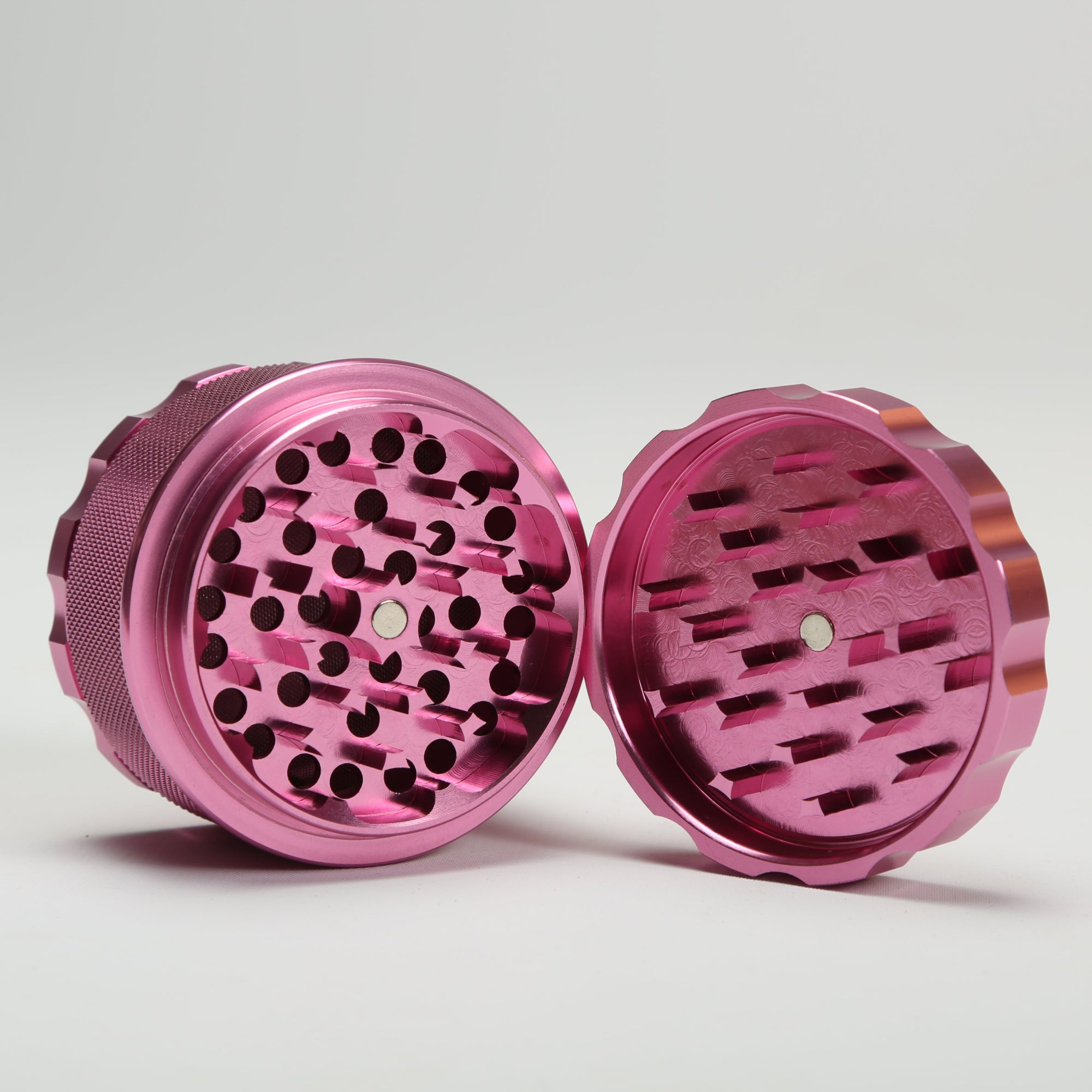 Pink metal grinder on a light gray background