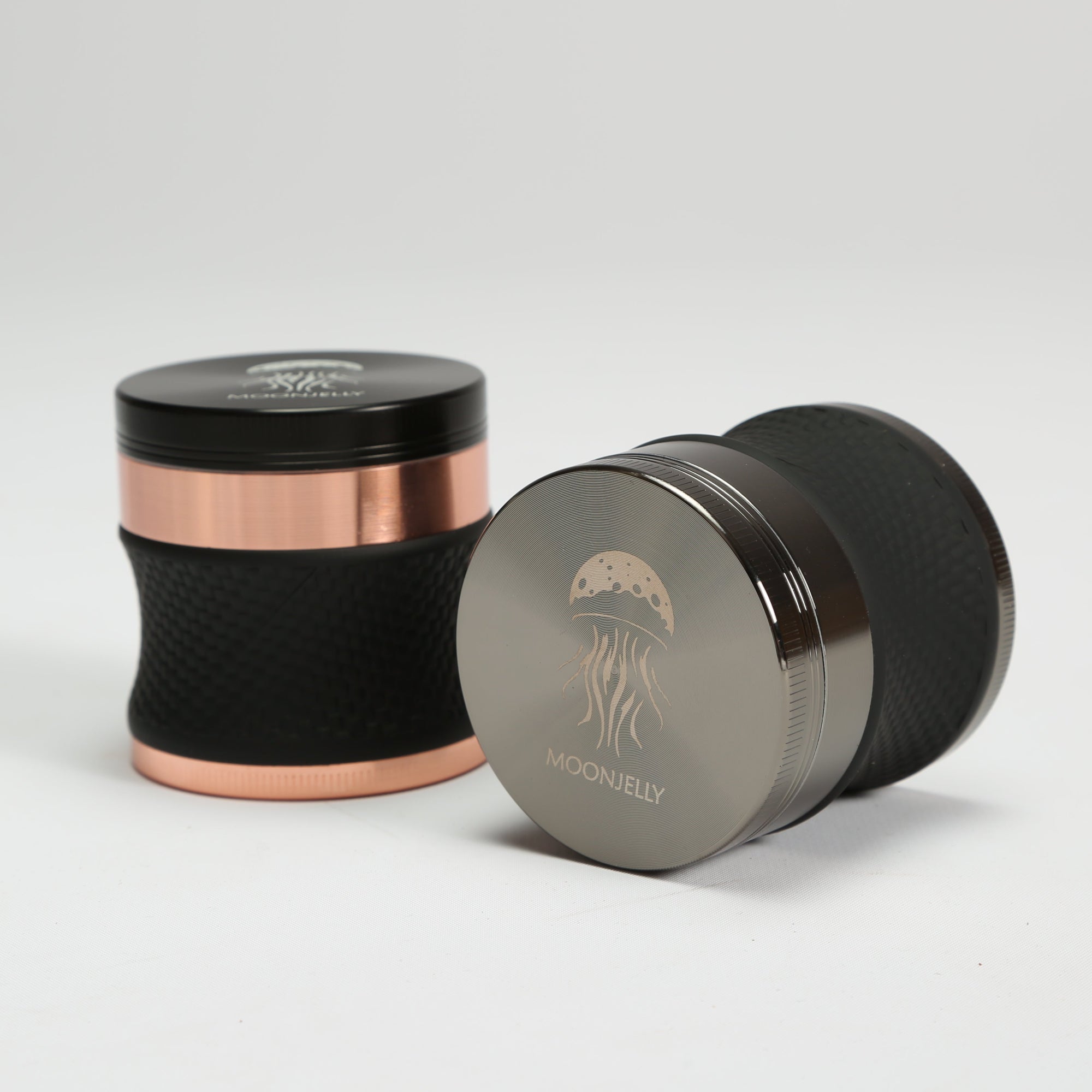 Two grinders with rose gold and black finishes on a light gray background