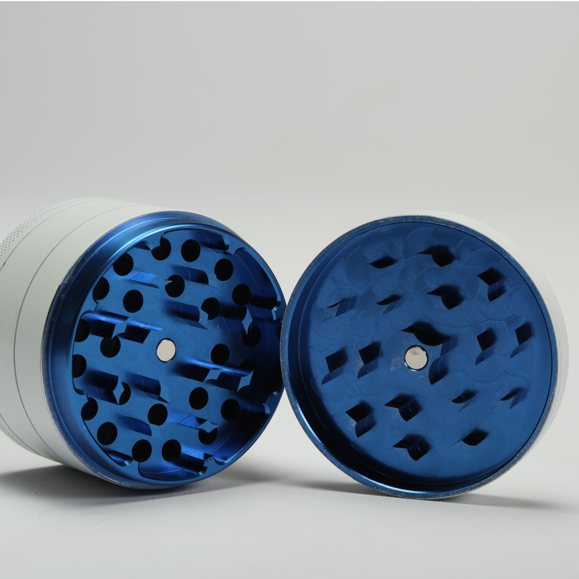 Blue and white metal grinder on a light gray background