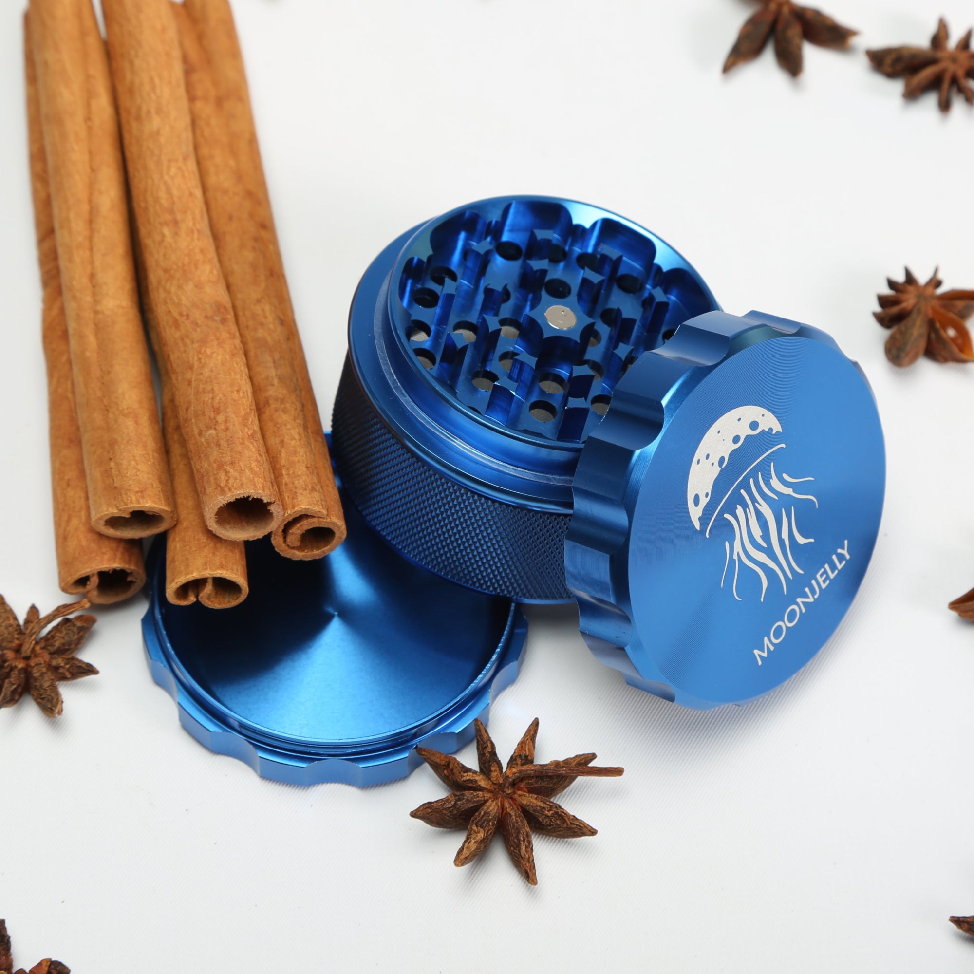 Blue herb grinder with cinnamon sticks and star anise on a white background 